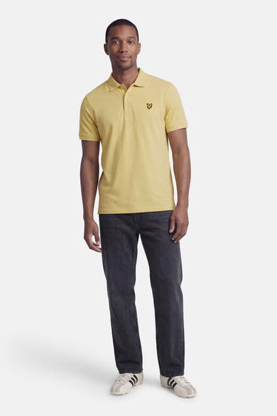 Groen poloshirt van LYLE & SCOTT, gedragen met een donkergrijze jeans en lage sneakers met strepen.