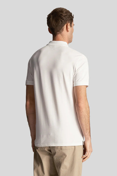 White short-sleeve polo shirt back view, smooth cotton fabric, classic fit, model wearing beige pants