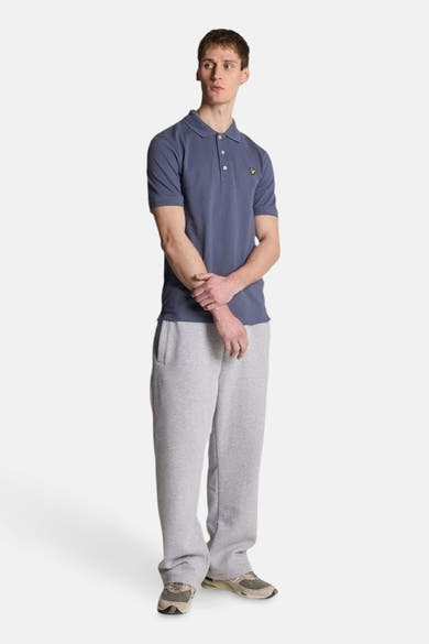 Blauw poloshirt met korte mouwen van LYLE & SCOTT, gedragen met een grijze joggingbroek en sneakers.