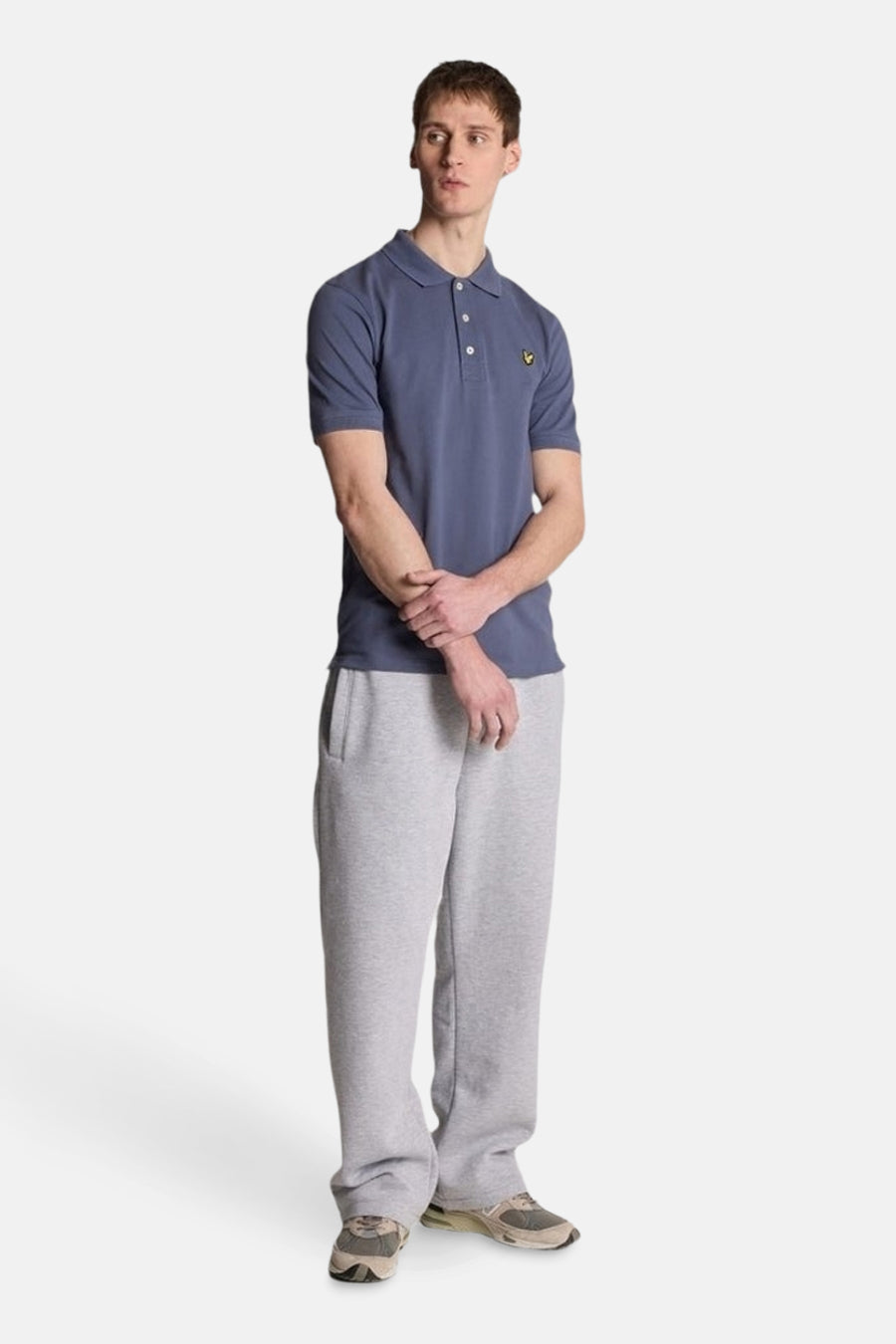 Blauw poloshirt met korte mouwen van LYLE & SCOTT, gedragen met een grijze joggingbroek en sneakers.