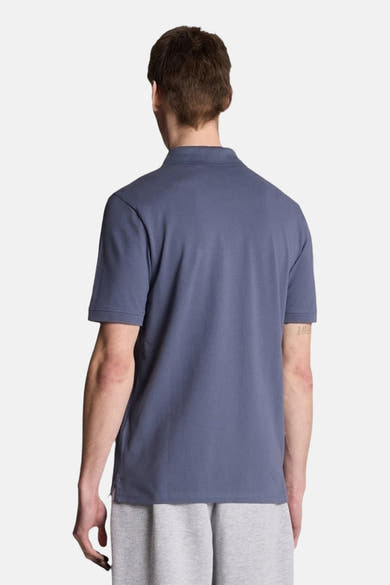 Polo à manches courtes bleu de LYLE & SCOTT, vue arrière, porté avec un pantalon de survêtement gris.