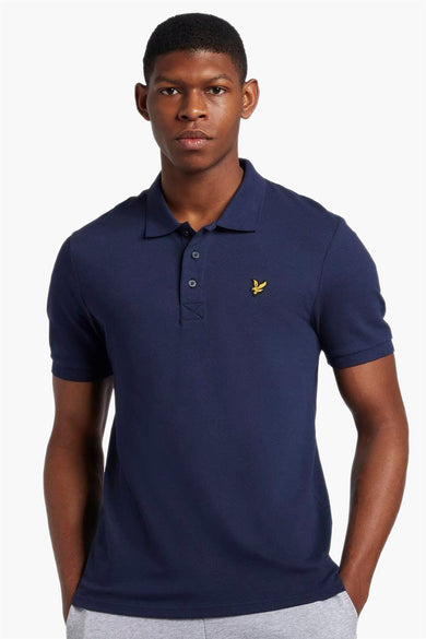 Navy blue short-sleeve polo shirt by Lyle & Scott, featuring yellow embroidered bird logo on chest, classic collar, and button placket, front view on model.