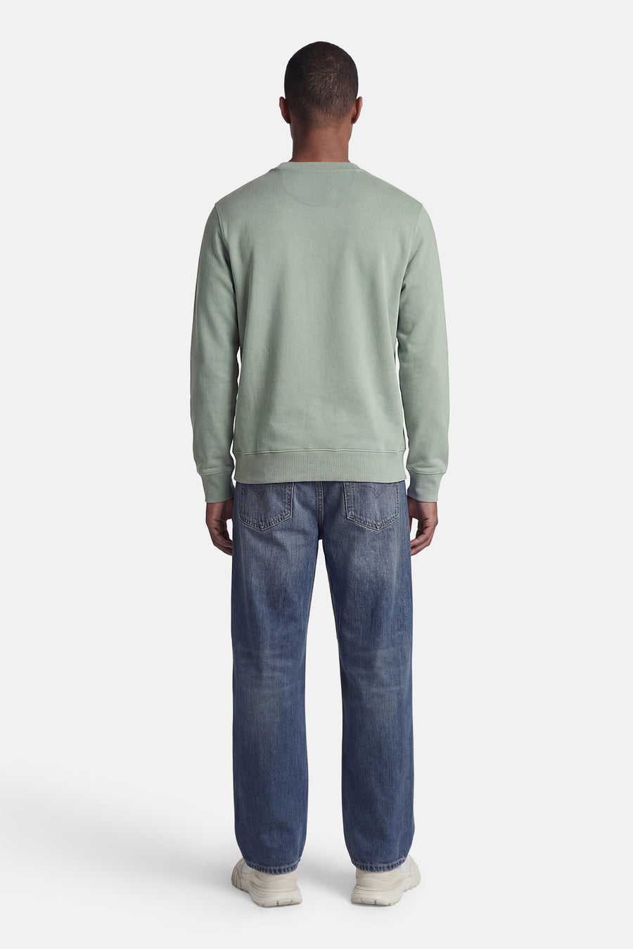 Groene STROM trui, ronde hals, achterkant zichtbaar, gedragen met een spijkerbroek en sneakers.