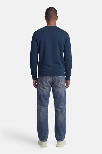 Blauwe STROM-sweater, ronde hals, achterzicht, gedragen met een spijkerbroek en sneakers.