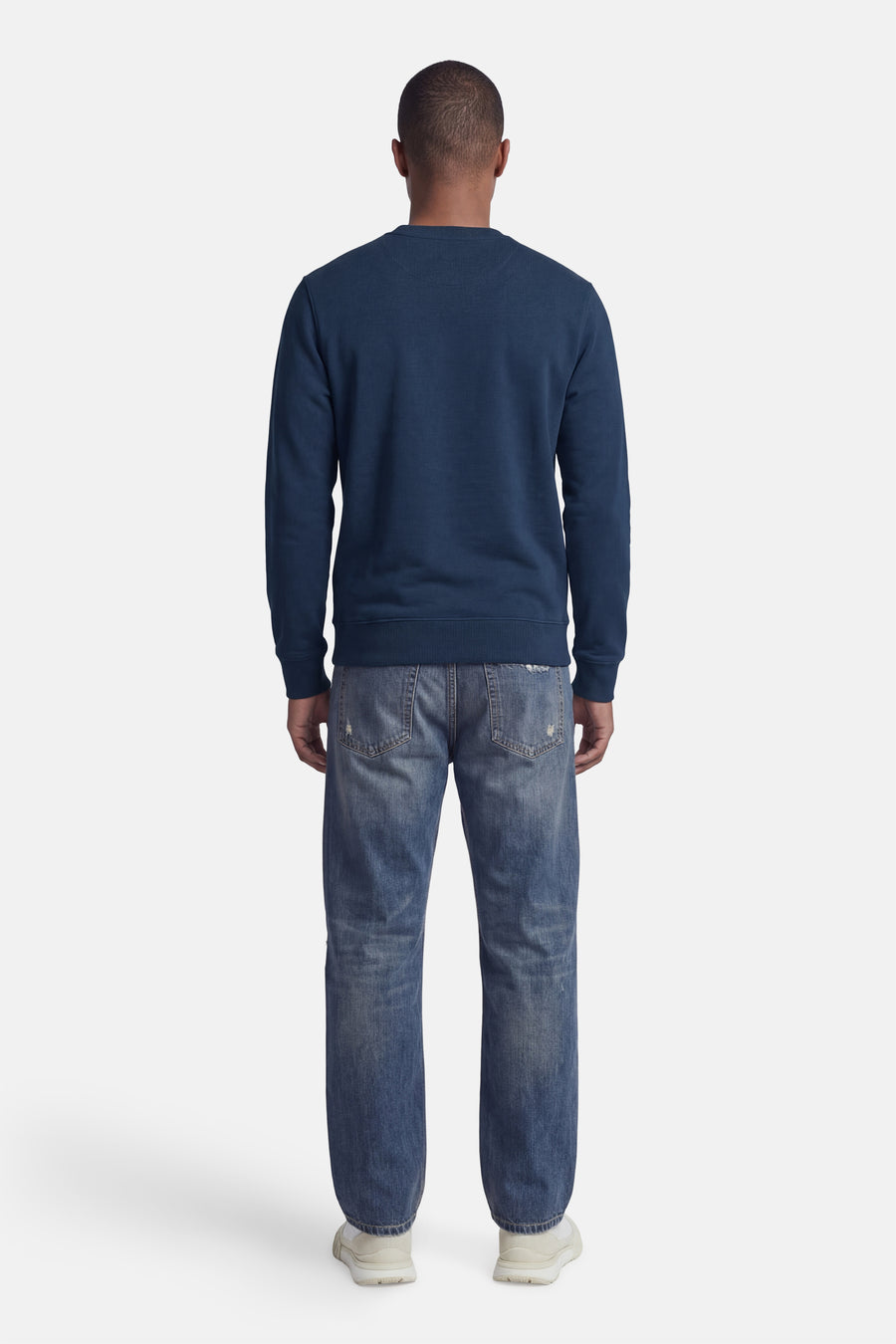 Blauwe STROM-sweater, ronde hals, achterzicht, gedragen met een spijkerbroek en sneakers.