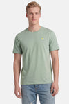 Groen T-shirt met korte mouwen van STROM met eimotief op de voorkant, gedragen door een man met een blauwe spijkerbroek.