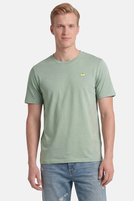 Groen T-shirt met korte mouwen van STROM met eimotief op de voorkant, gedragen door een man met een blauwe spijkerbroek.