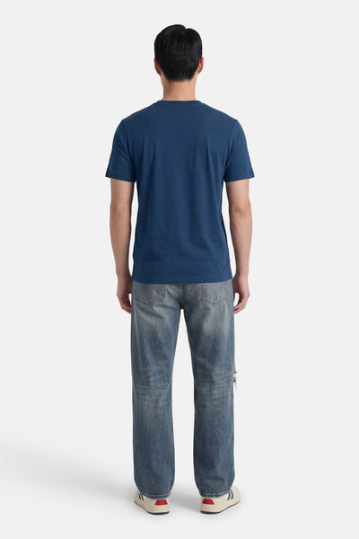Blauw STROM T-shirt met korte mouwen, van achteren gedragen met een verbleekte spijkerbroek en sneakers.