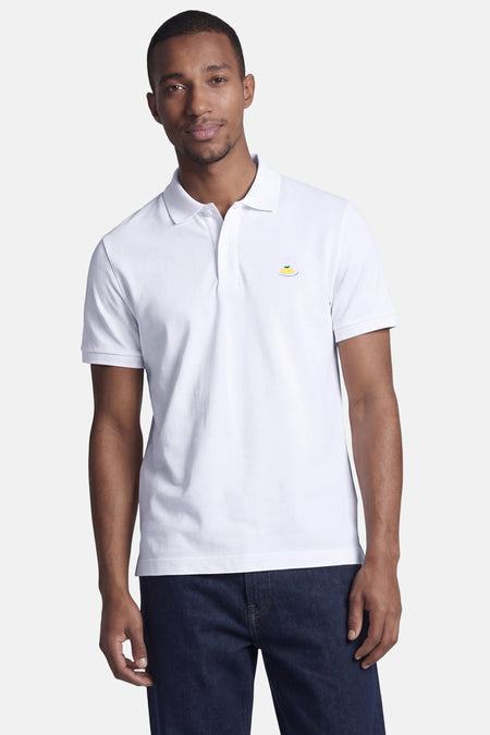 Witte STROM polo met korte mouwen, geborduurd patroon van pastagerecht, gedragen met een donkerblauwe jeans.
