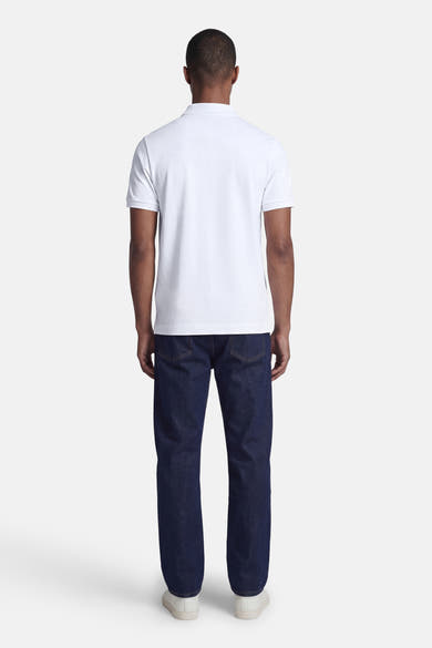 Wit STROM poloshirt, van achteren gedragen door een man met een donkerblauwe spijkerbroek en witte sneakers.