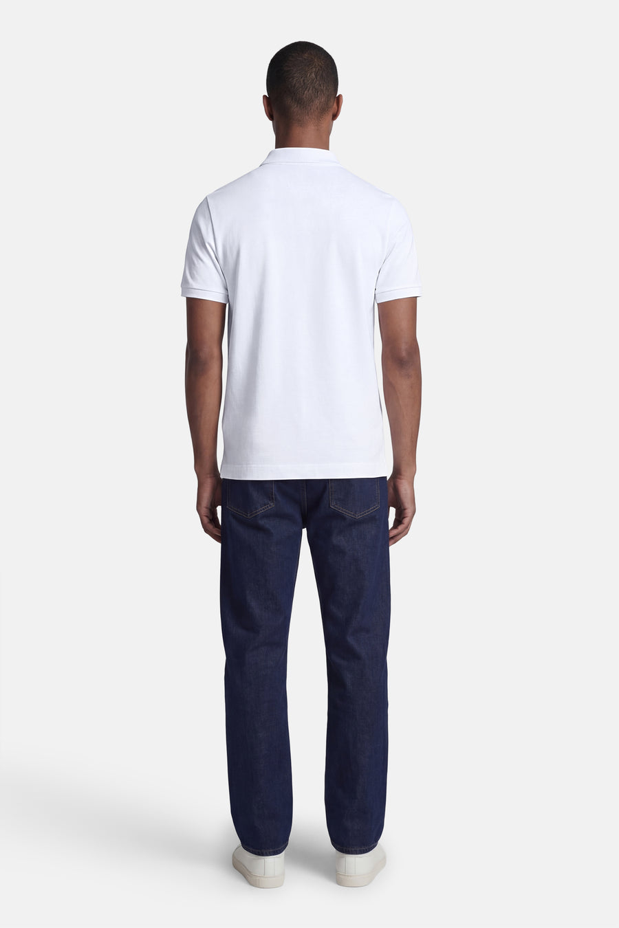 Wit STROM poloshirt, van achteren gedragen door een man met een donkerblauwe spijkerbroek en witte sneakers.
