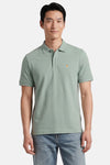Groen STROM poloshirt met klein oranje en roze patroon, gedragen door een man in een blauwe spijkerbroek.