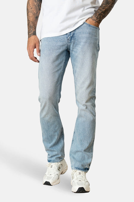 Jean droit en denim bleu clair de Petrol Industries®, porté avec un t-shirt blanc et des baskets blanches