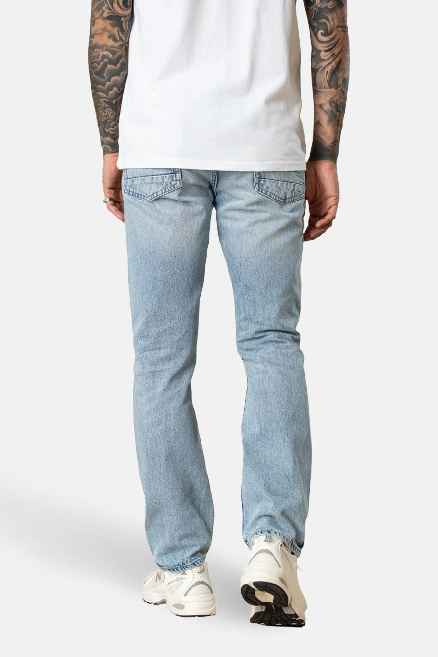 Jeans droit en denim bleu clair de Petrol Industries, avec poches arrière apparentes et chaussures de sport blanches.
