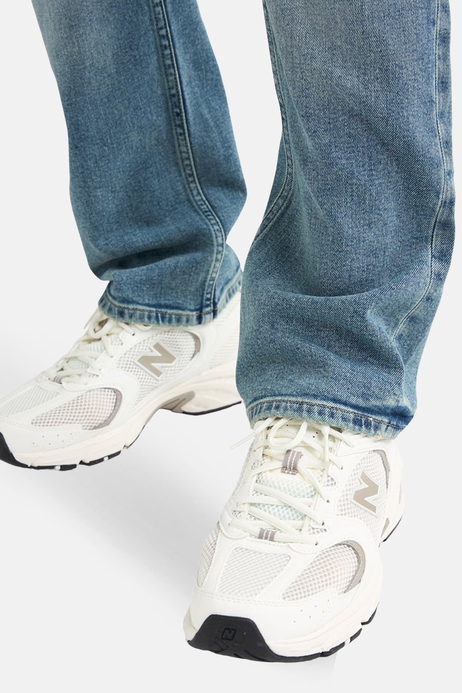 Jean droit en denim bleu clair de Petrol Industries®, porté avec des chaussures de sport blanches.
