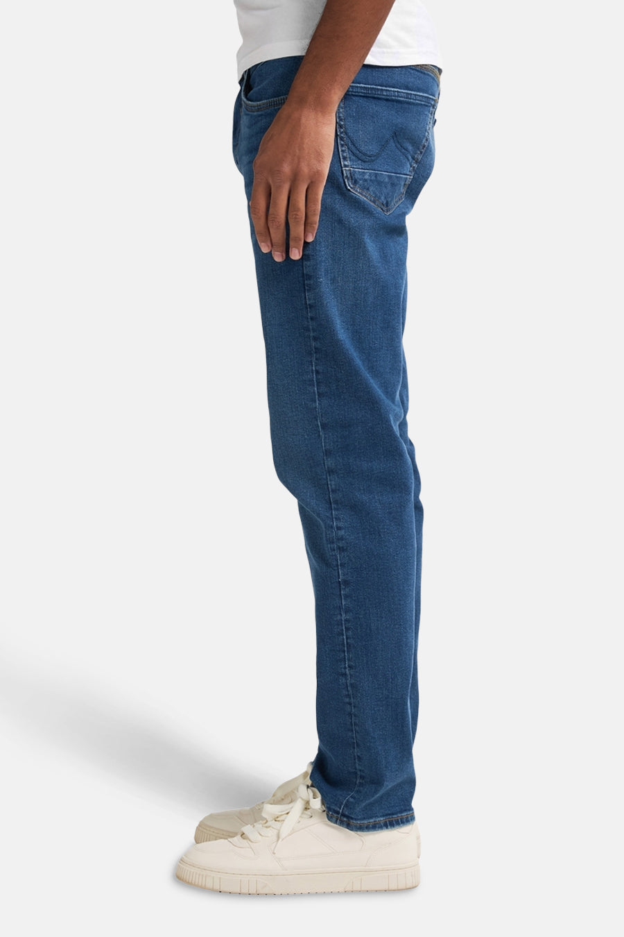 Rechte spijkerbroek in middinblauw denim van Petrol Industries, gedragen met witte sneakers.