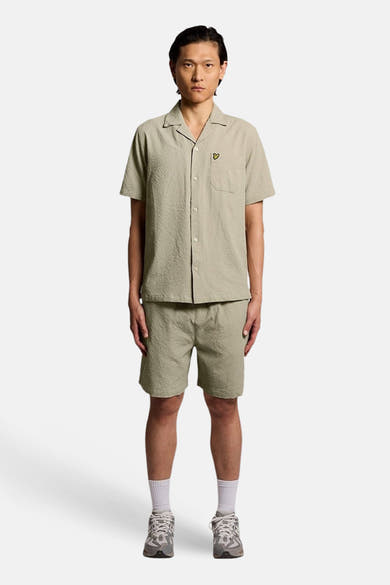 Groen overhemd met korte mouwen van LYLE & SCOTT, met textuurpatroon, gedragen met een bijpassende korte broek, witte sokken en sportschoenen.