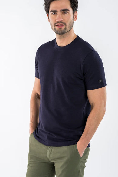 T-shirt bleu à manches courtes de PRESLY & SUN, porté avec un pantalon kaki, mains dans les poches.