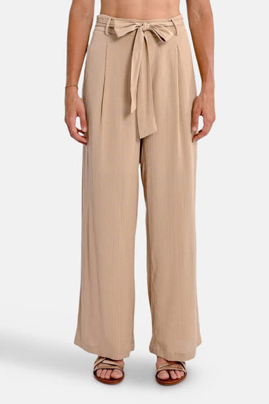 Beige broek van Molly Bracken, losse pasvorm met strikceintuur in de taille, gedragen met sandalen.