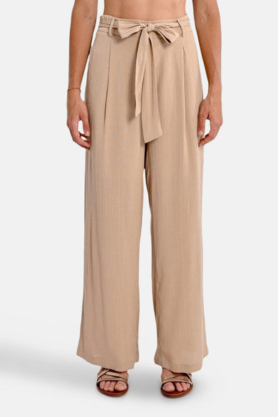 Beige broek van Molly Bracken, losse pasvorm met strikceintuur in de taille, gedragen met sandalen.