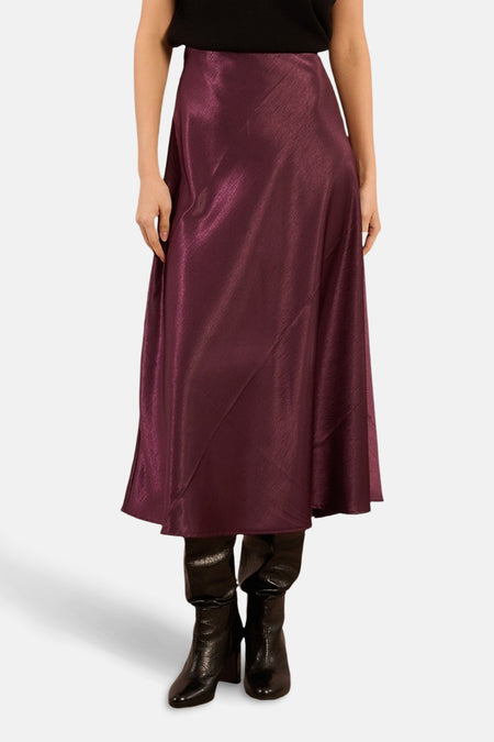 Glanzende paarse lange rok van Molly Bracken, met asymmetrische zoom en gedragen met zwarte laarzen.