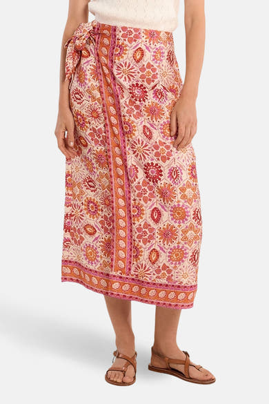 Jupe longue multicolore de Molly Bracken, imprimé floral fantaisie, nouée à la taille, portée avec des sandales plates.