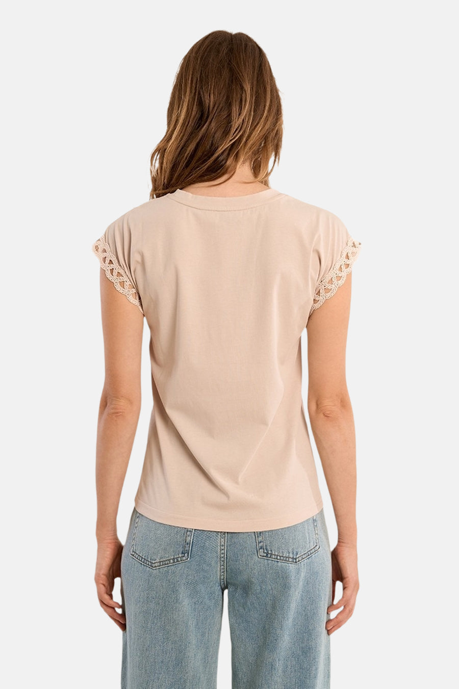 Top sans manches beige de Molly Bracken, avec manches à bordure en dentelle, porté avec un jean.