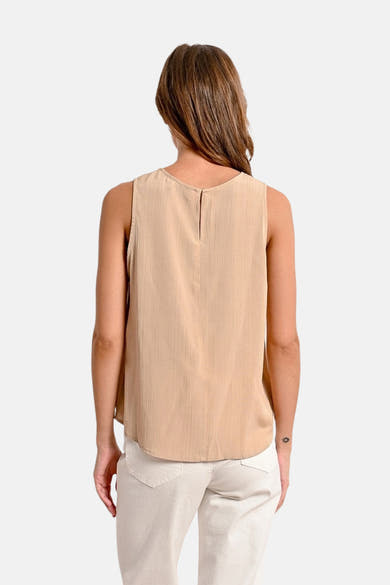 Mouwloos beige hemd van Molly Bracken, met een kleine opening aan de achterkant, gedragen met een witte broek.
