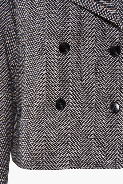 Veste courte noire par Molly Bracken, avec motif à chevrons et boutons décoratifs.