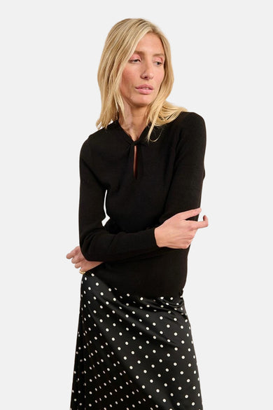 Pull noir à col rond de Molly Bracken, porté avec une jupe à pois.
