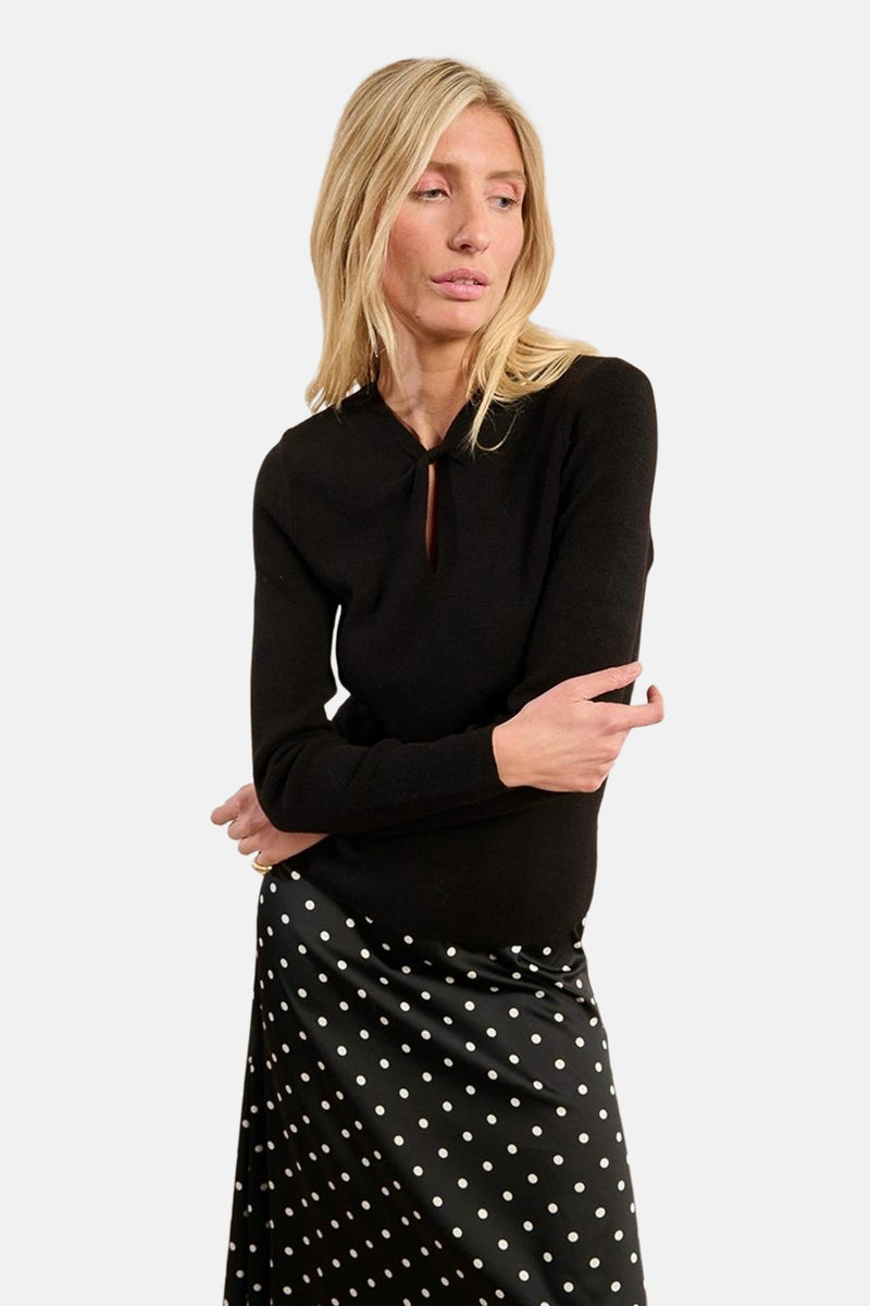 Pull noir à col rond de Molly Bracken, porté avec une jupe à pois.
