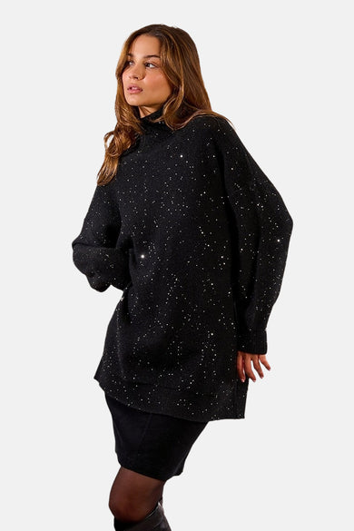 Zwarte jurk met lange mouwen van Molly Bracken, versierd met glinsterende pailletten, gedragen met een zwarte panty.