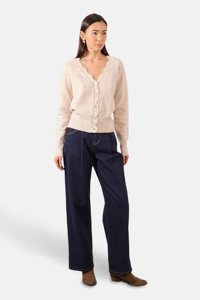 Beige vest, van Molly Bracken, met geschulpte rand en gedragen met een wijde jeans en suède laarzen.
