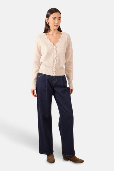 Beige vest, van Molly Bracken, met geschulpte rand en gedragen met een wijde jeans en suède laarzen.