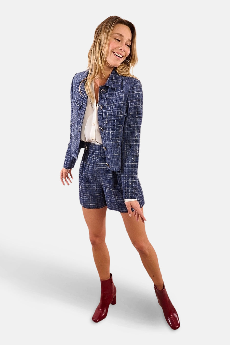 Korte blauwe rok van Molly Bracken, geruit met een bijpassende blazer en bordeauxrode enkellaarsjes.