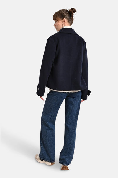 Korte marineblauwe jas van Molly Bracken, met een klassieke kraag en lange mouwen, gedragen over een wijde jeans.