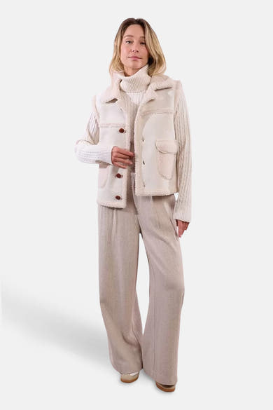 Beige mouwloos vest van Molly Bracken met bruine knopen, gedragen over een kabelgebreide trui.