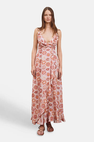 Robe multicolore de Molly Bracken, avec imprimé floral et décolleté plongeant, portée avec des sandales marron.