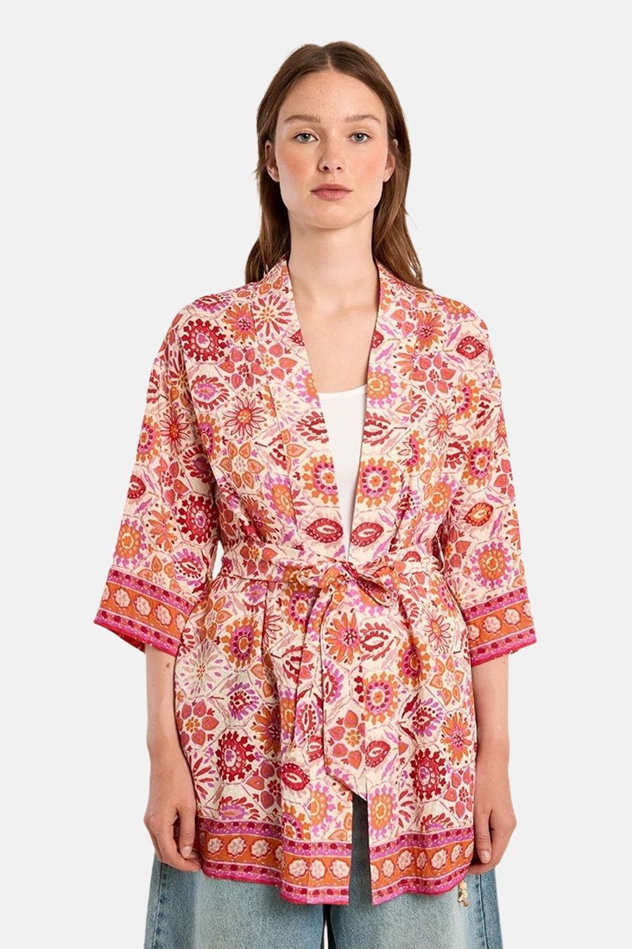Multikleurend gilet van Molly Bracken, met bloemenpatroon, gedragen over een witte tanktop en een wijde jeans.