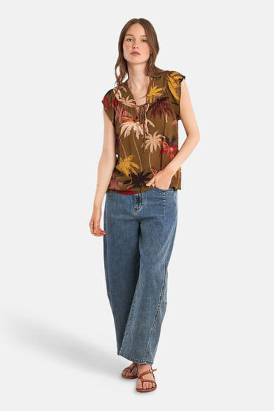 Chemisier à manches courtes multicolore de Molly Bracken avec motif de palmiers, porté avec un jean bleu.