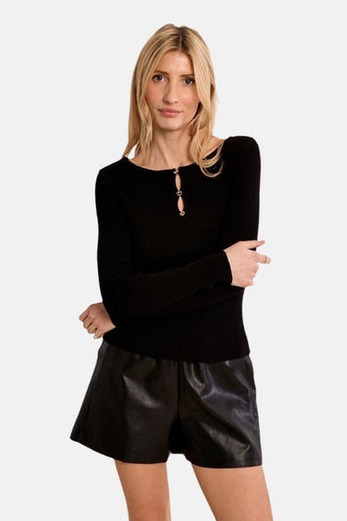 Black ribbed O-neck long-sleeve sweater with front keyhole and silver heart-shaped hardware, worn with shiny black shorts, front view