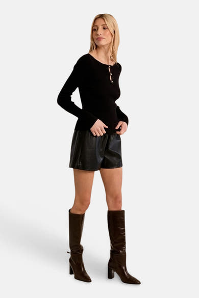 Black ribbed O-neck long-sleeve sweater with front buttons, worn with black leather shorts and brown knee-high boots, full-length lifestyle view