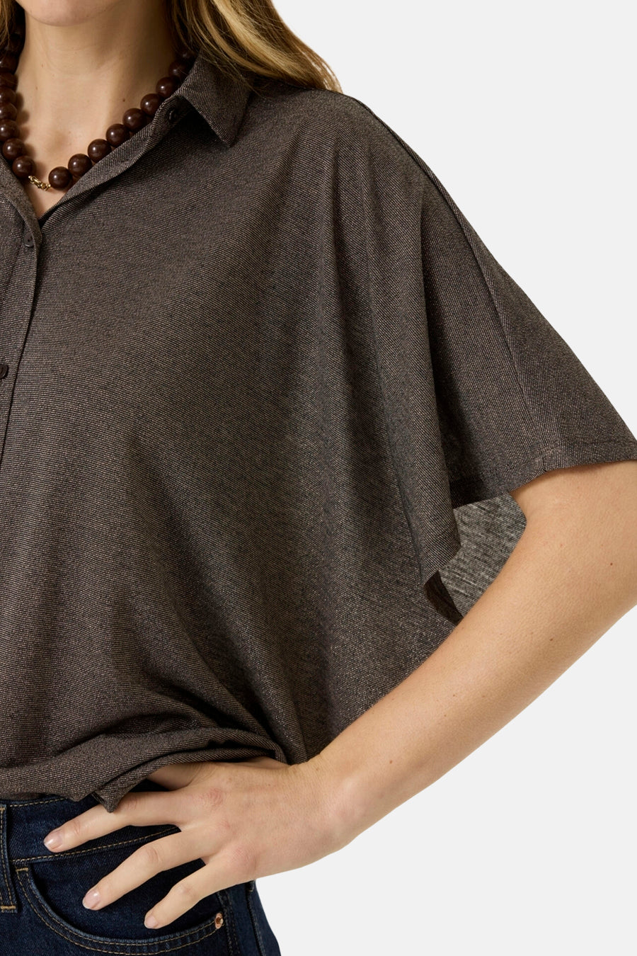 Brown 3/4-sleeve blouse with textured fabric, button-down collar, and side view styling worn with dark jeans and wooden bead necklace.
