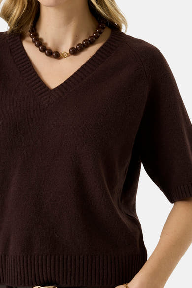 Brown V-neck sweater with ribbed trim and short sleeves, worn with dark beaded necklace, front cropped view
