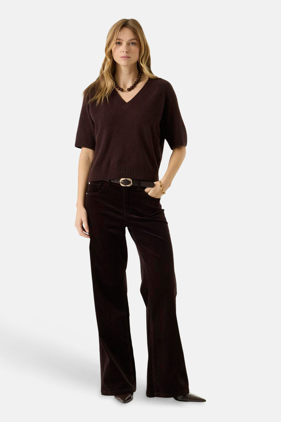 Brown V-neck short-sleeve knit sweater with ribbed hem and cuffs, worn with dark corduroy pants and belt, full-length front view