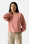 Coral crewneck sweater with soft textured knit, relaxed fit, and ribbed cuffs, worn with beige pants in front view