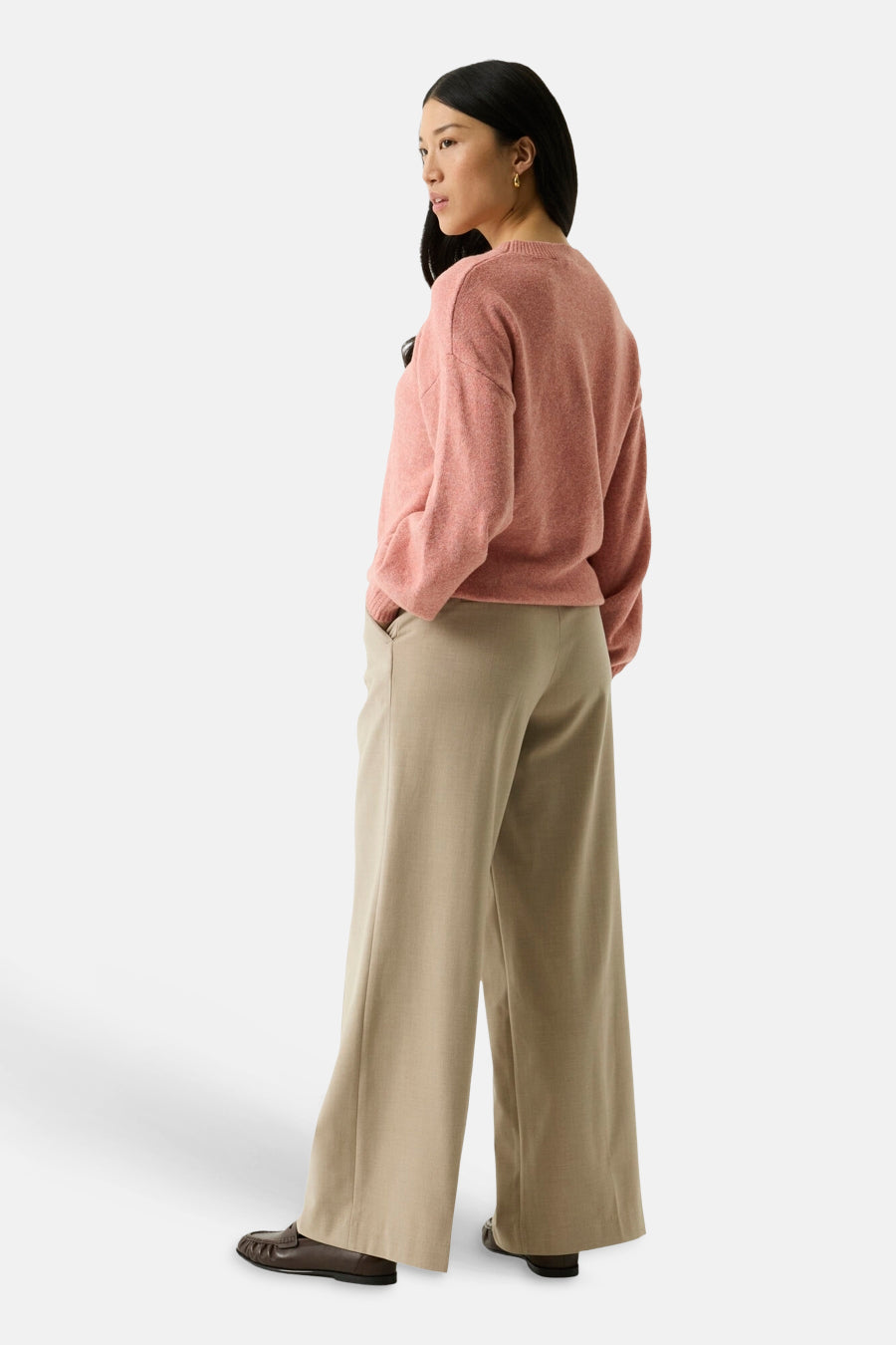 Coral O-neck sweater with soft textured knit, side view on model wearing wide-leg beige trousers and brown loafers