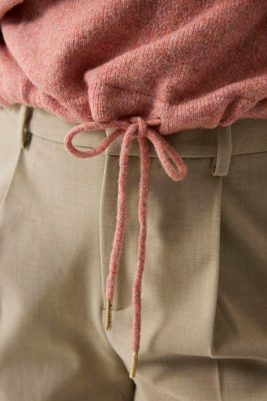 Coral marled O-neck sweater with ribbed hem and matching drawstring, tied at waist over beige trousers, close-up view