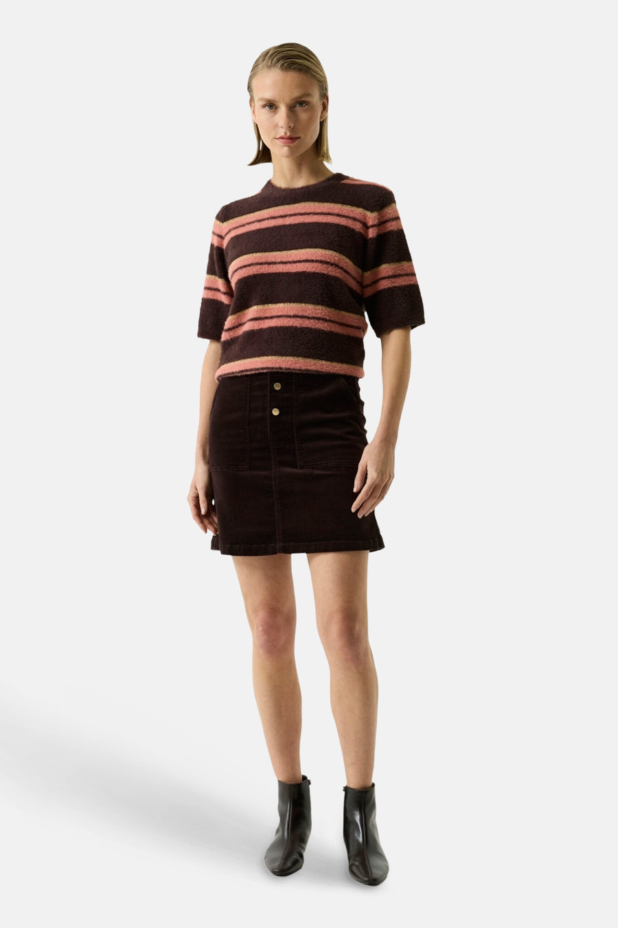 Multicolored striped O-neck sweater with short sleeves and fuzzy texture, worn with dark corduroy skirt and black boots, front view