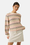 Ecru O-neck sweater with scalloped knit pattern in cream, pink, and brown, worn with corduroy skirt, front view